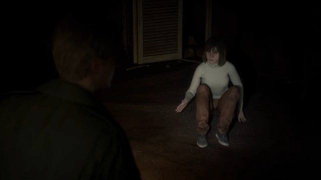 Remake de Silent Hill 2 : Angela se recroqueville sur le sol tandis que James lui braque une lampe de poche.