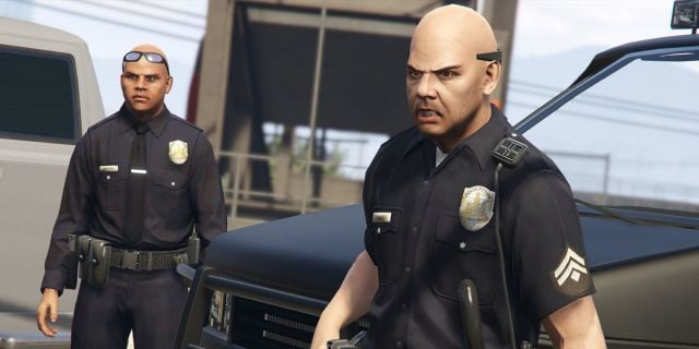 Deux policiers debout devant une voiture de police dans GTA V.